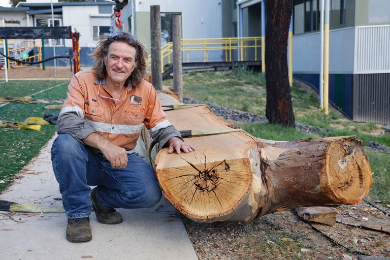 Paul McKay from Julia's Onsite Timber Milling with a cut log at Doreen Primary School
