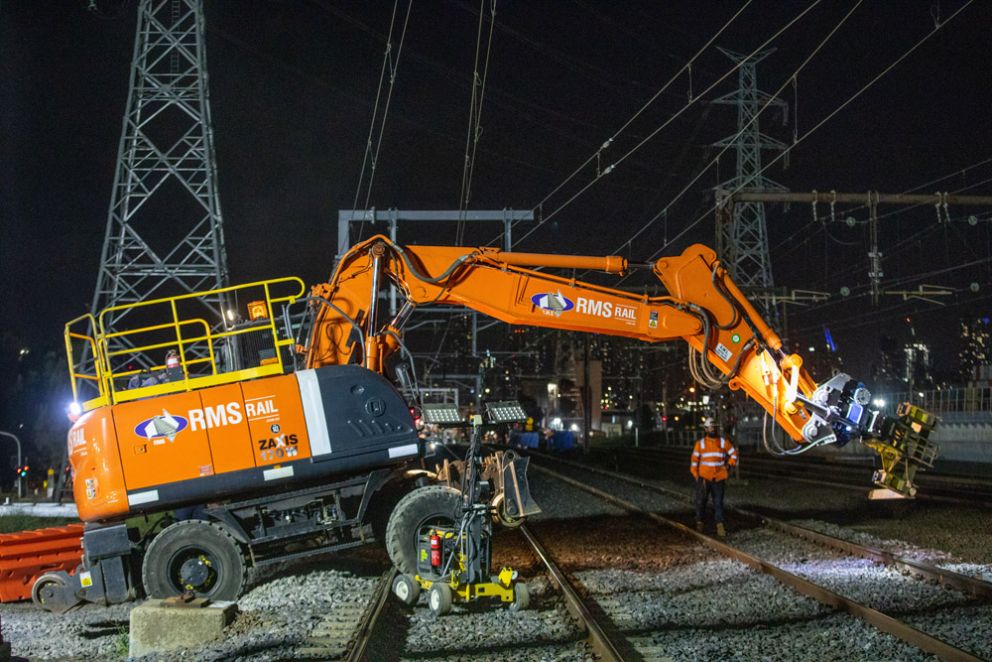 A high rail machine preparing for works on the train tracks at night alongside a spotter