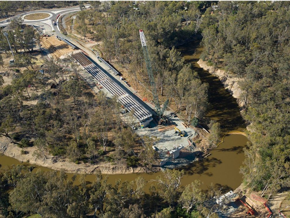 Birds eye image of the Campaspe River bridge beam intallation. The image shows the river running through the middle and a roundabout behind the bridge installlation