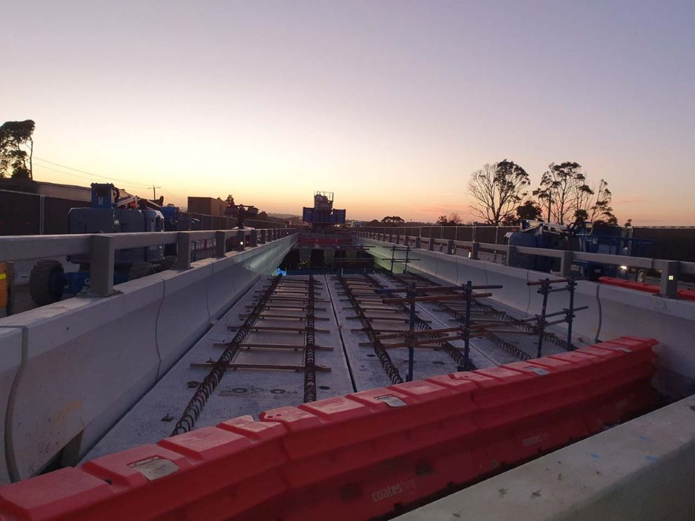 December 2020 Beams installed at Jacksons Road and Police Road to fill the bridges ready for new lanes. Image shows work being done on the bridge with the sunset in the background.