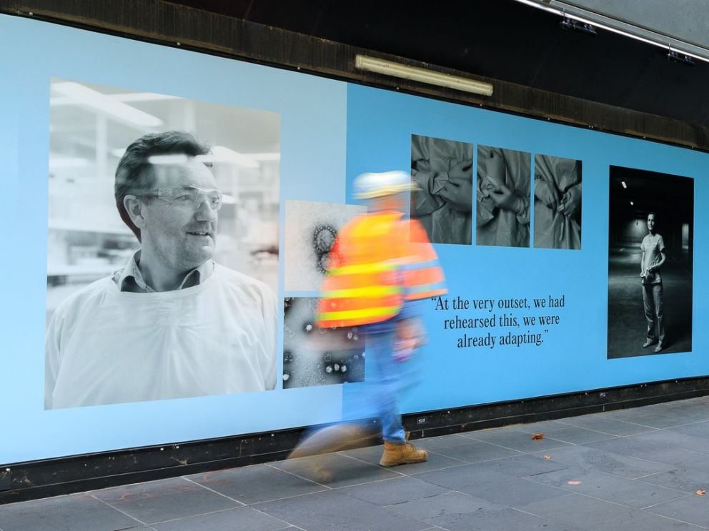 A person wearing hi-vis walks past artwork on Swanston Street