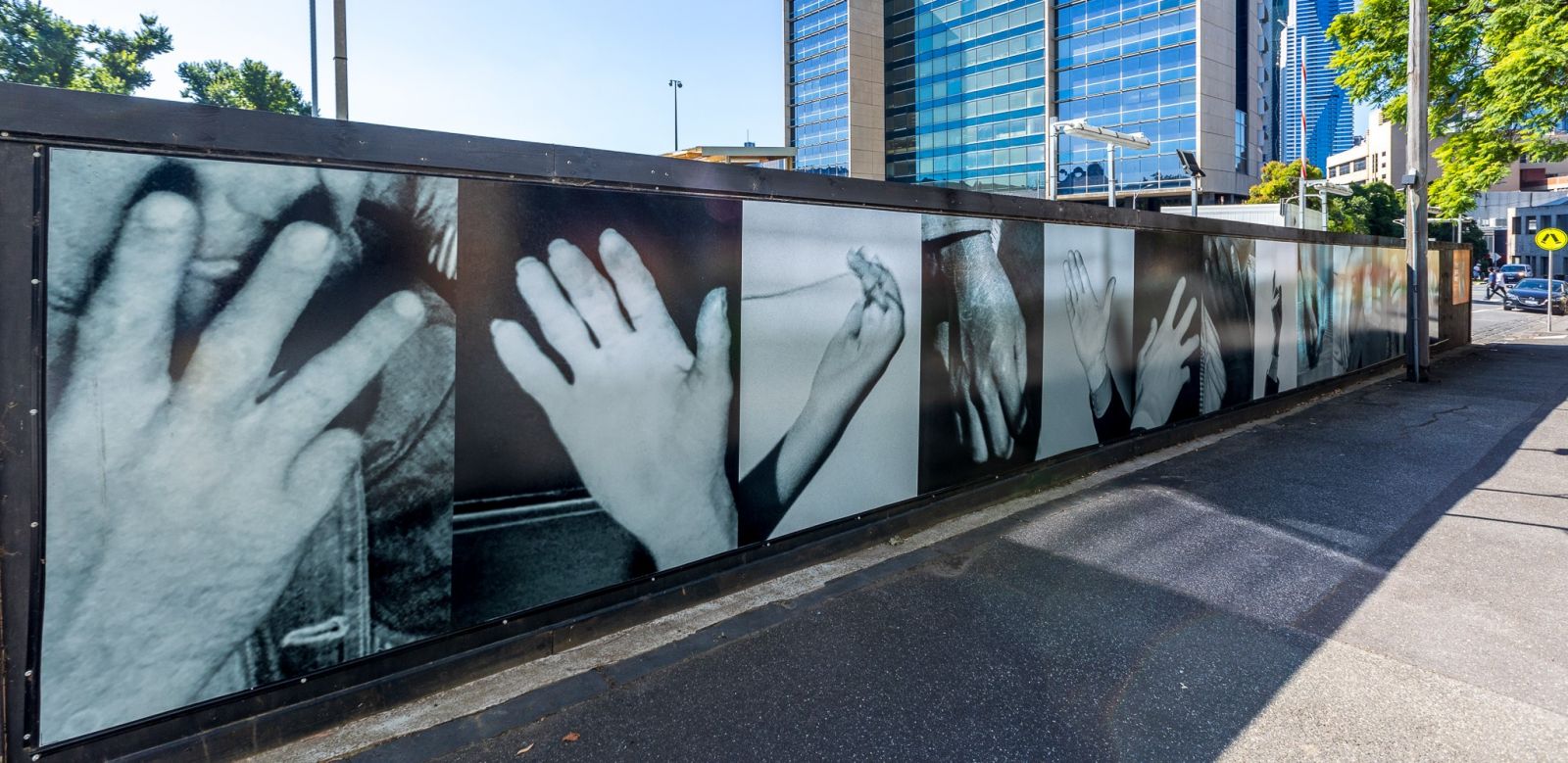 Artwork on sidewalk wall depicting hands.