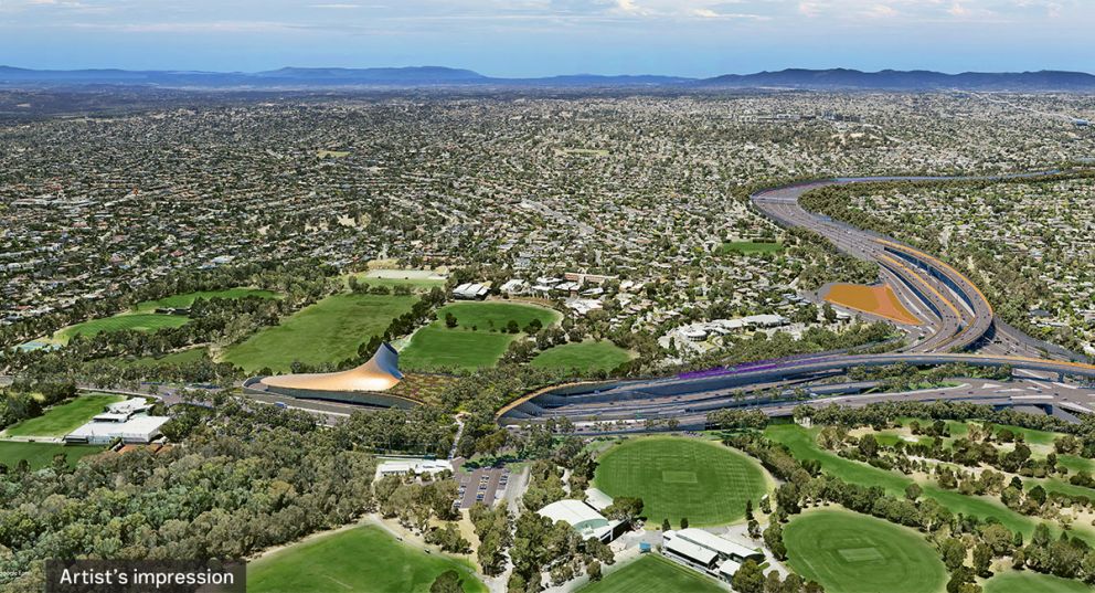 Artist’s impression aerial view looking east of Yarra Link green bridge, Eastern Freeway interchange and southern tunnel ventilation structure, Bulleen. The design for the ventilation structure is inspired by traditional Wurundjeri eel traps. Solar panels on the structure will help power the tunnels below. 