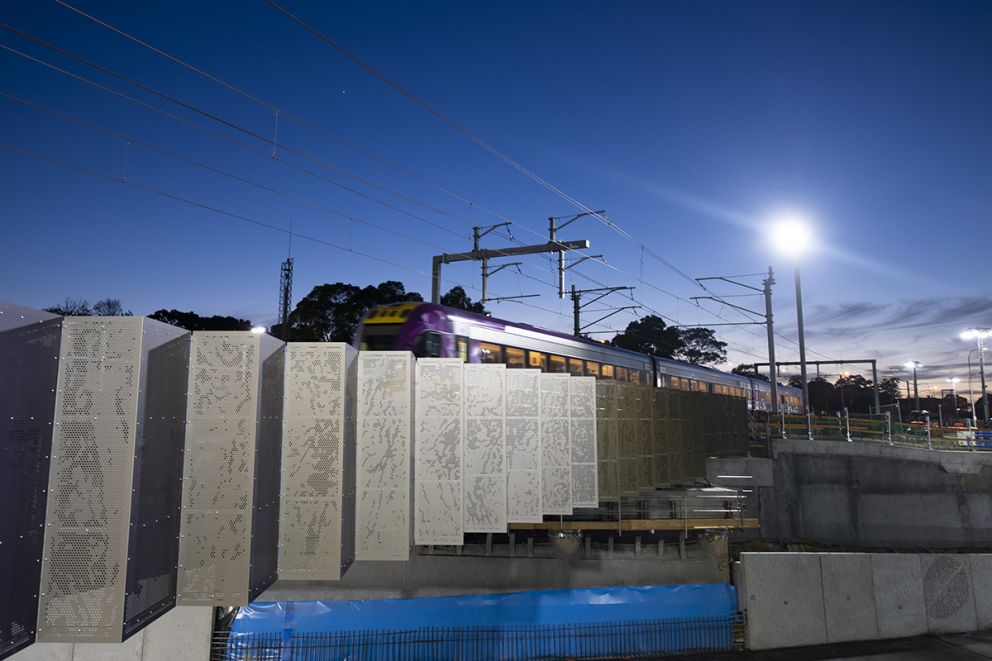 Perforated aluminium panels form images of the local area on the rail bridge