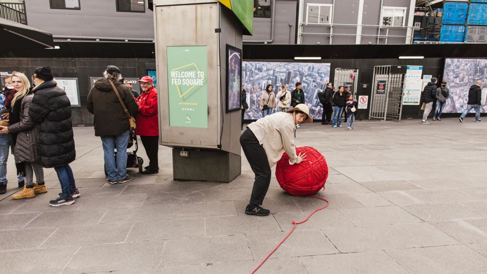 man pushes big ball of yarn