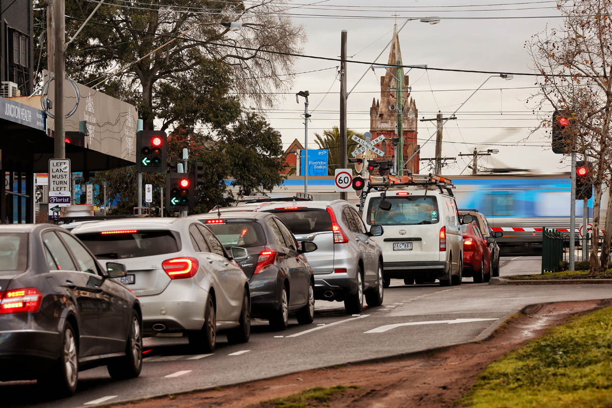 Cars waiting at Buckley Street level crossing as a train passes through.