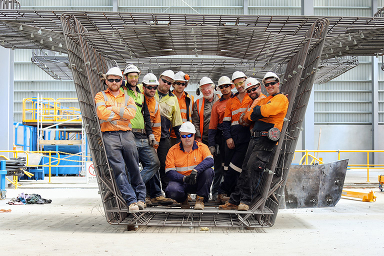 Workers standing inside a large metal frame of a beam