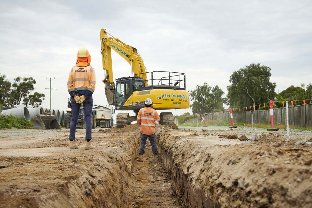 Excavating trenches in preparation for laying a new drainage network, under the watchful eye of our safety spotters