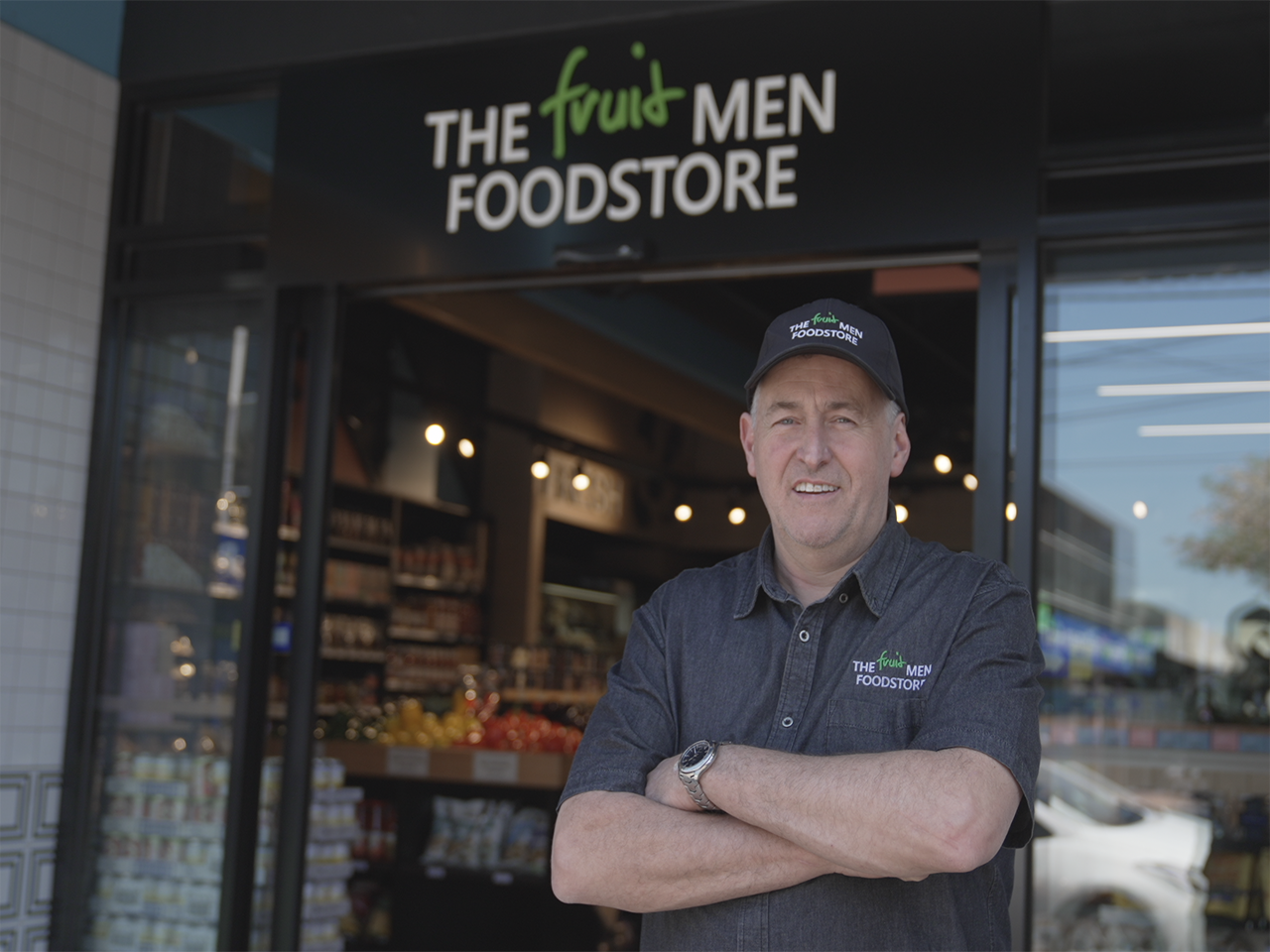 The owner of the Fruit Men Food Store standing in front of his business.