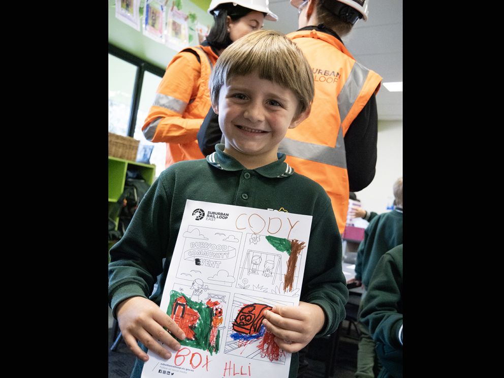 Image shows Cody, a primary school student proudly showing off his Burwood themed colouring sheet