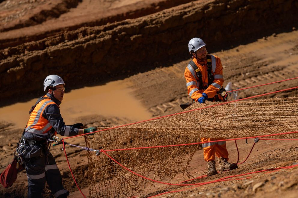 Crews abseiling down the Bogong High Plains Rd landslip to install anti-erosion mesh