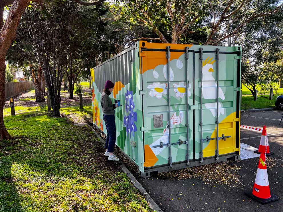 Image shows Melbourne artist Angharad Neal-Williams in the processes of painting a container