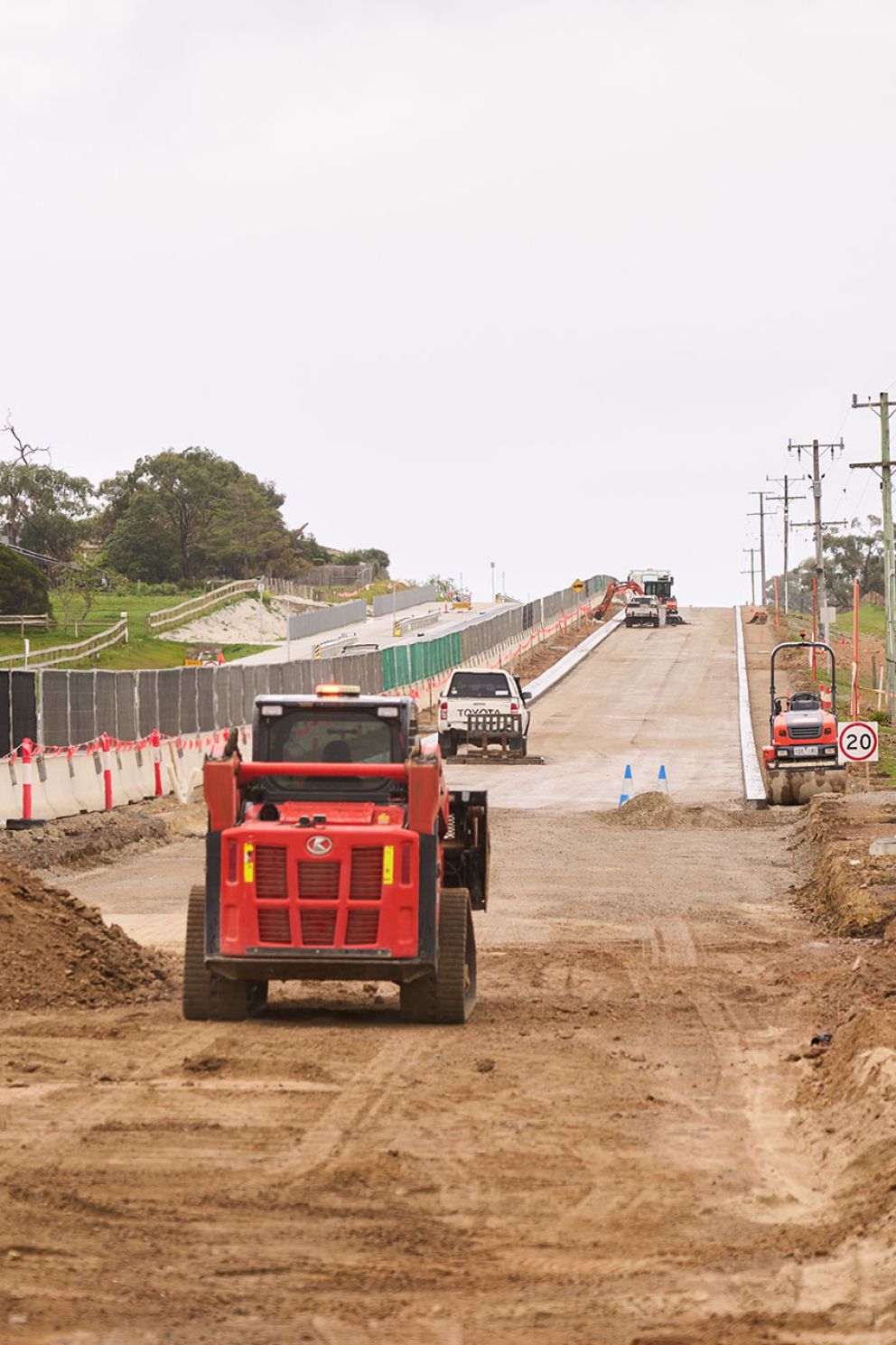 A digger removing existing road layers to prepare for new lane foundations one scoop at a time