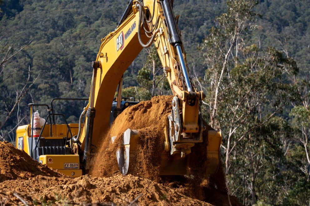 An excavator digs out material to shape large benches