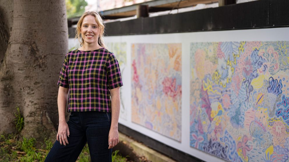 Jess Hall standing in front of her artwork