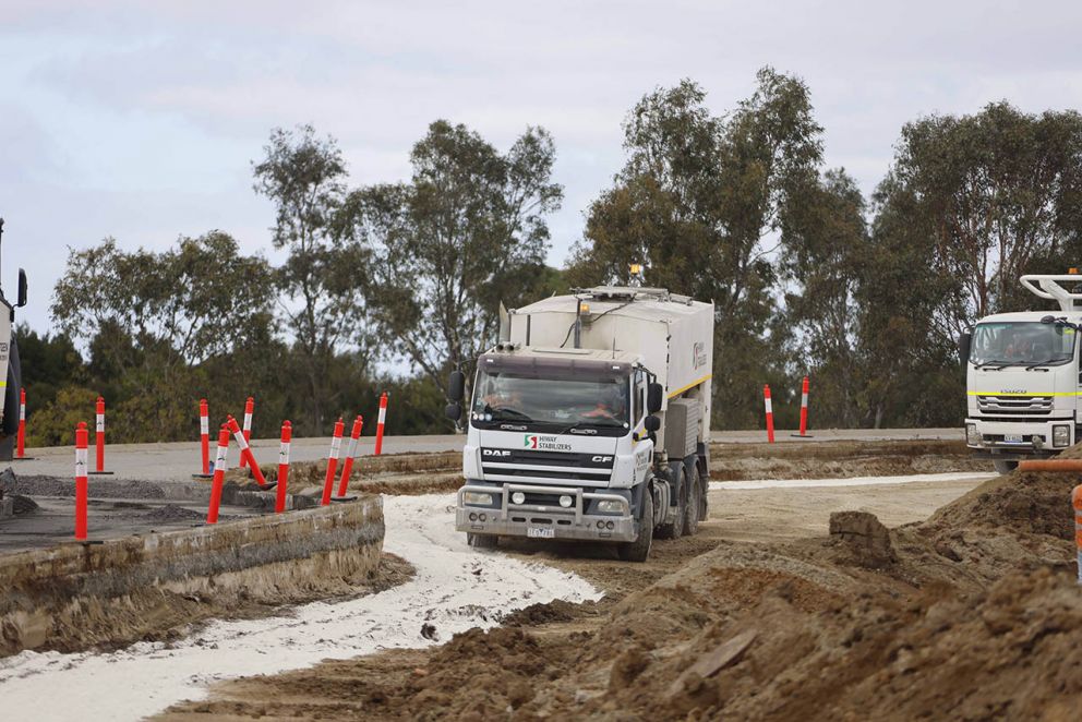 A spreader truck adding lime and cement to stabilise the soil.