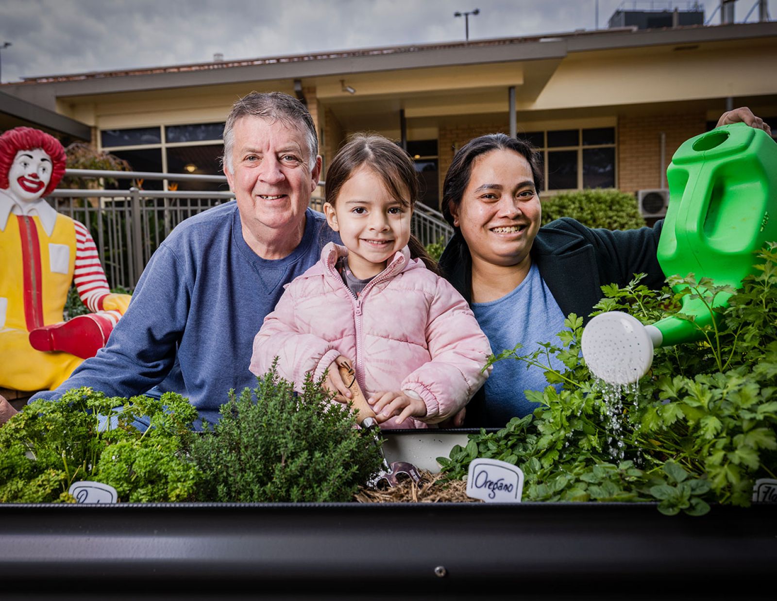 Family smiling together as they water new garden beds at the Ronald Mcdonald house