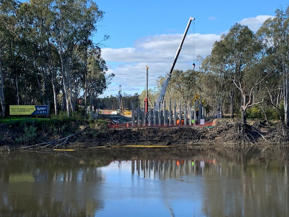 Image of the Murray River with construction occurring in the background. There is also a sign by Major Road Projects Victoria stating that they are building a second river crossing there