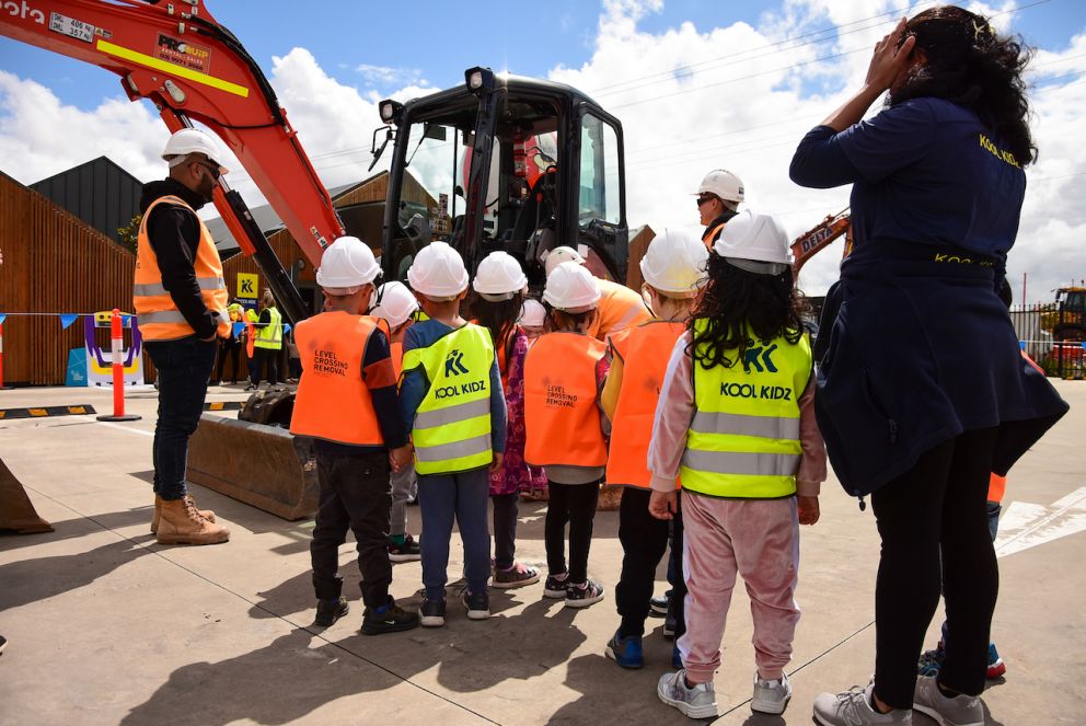 Children in hi-vis looking at construction machinery.