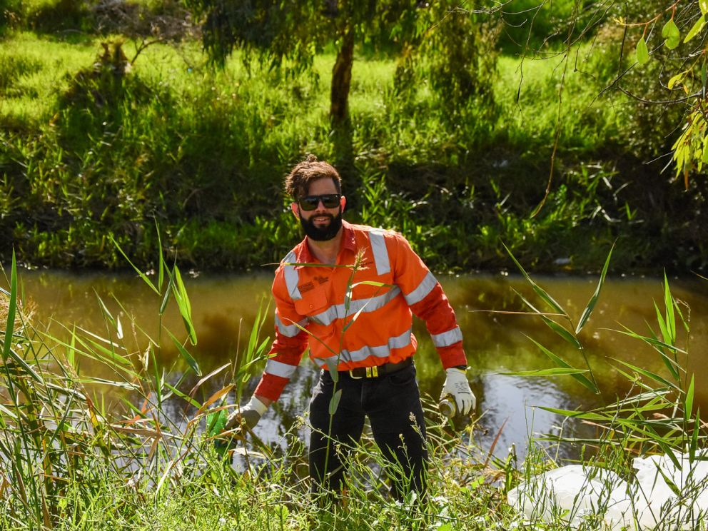 A man in hi-vis standing in the grass with a rubbish bag