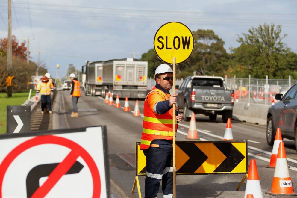 A traffic controller keeping road users and construction workers safe on Narre Warren North Road