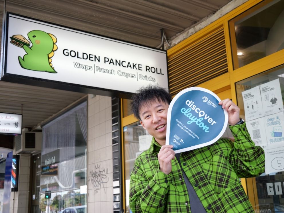 Business owwner of Golden Pancake Roll hold up a discover clayton sign