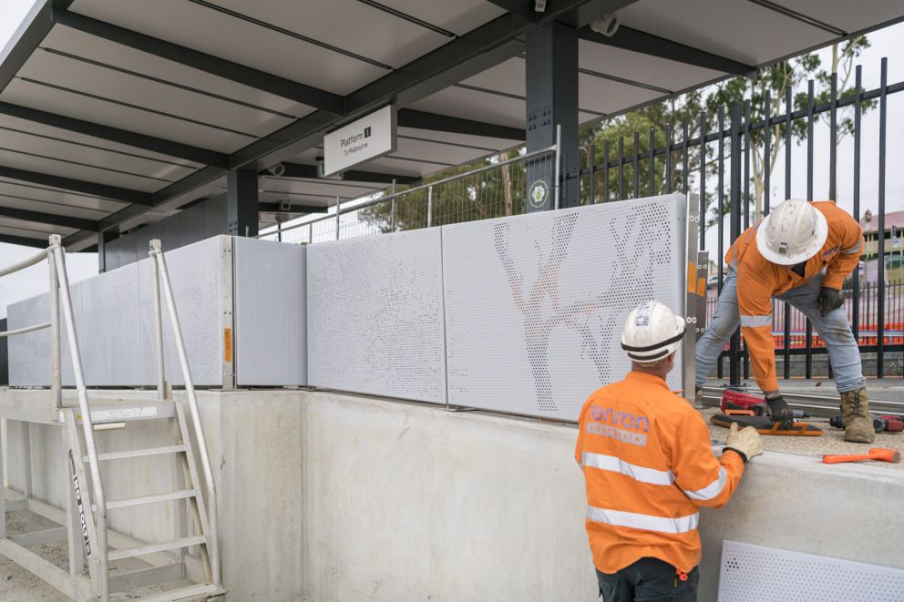 Workers installing the aluminium sheeting adjacent to the station platform