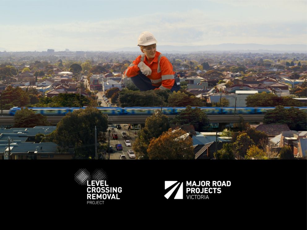 Suburban landscape, with a train going over a raised railway next to a giant worker in a high-vis shirt and hard hat. Logos for Level Crossing Removal Project and Major Road Projects Victoria.