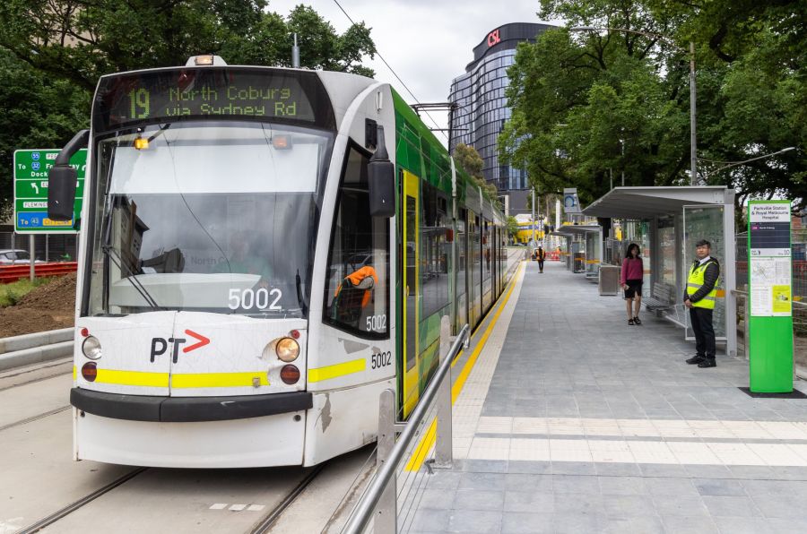 A tram with route 19 North Coburg displayed pulling up to a raised tram stop with shelter
