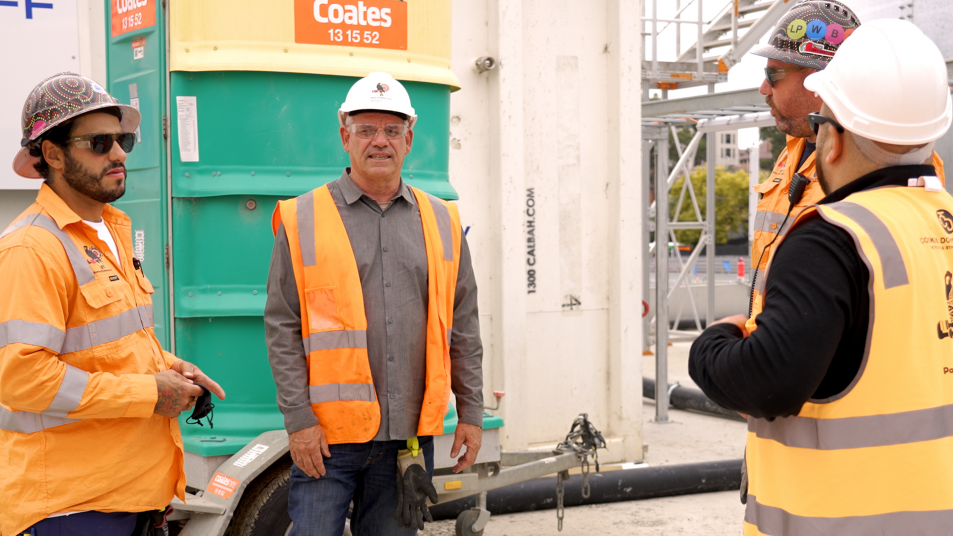 Four males wearing PPE gathered around a worksite