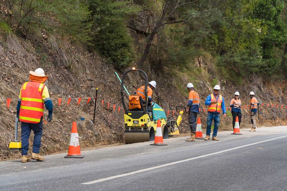 A small roller prepares the road base for new asphalt