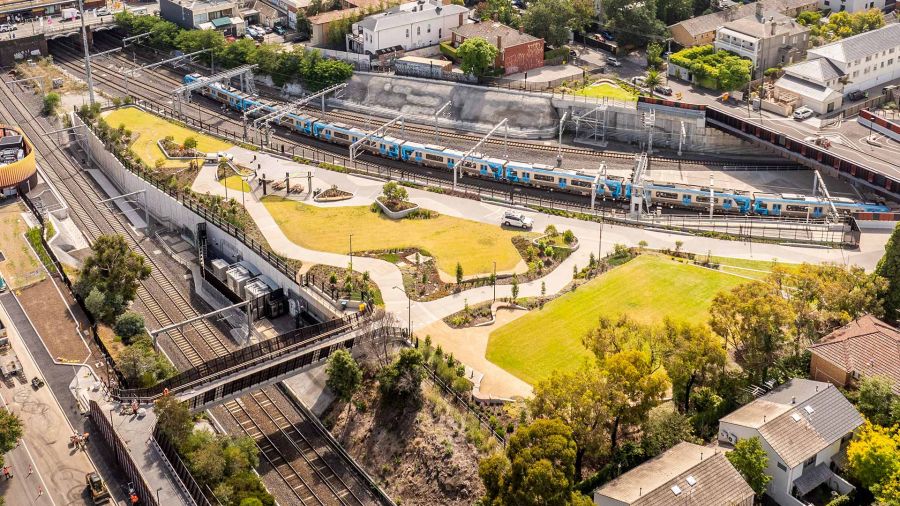 Drone view of the South Yarra siding reserve park in the middle of 2 major rail corridors, with a train passing through