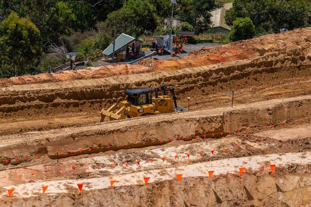 A machine working to clear material from the bottom bench on the landslip