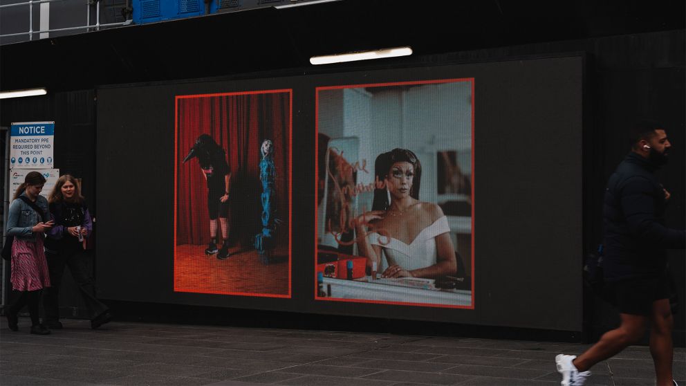 Images on a digital screen with a red border on a black hoarding