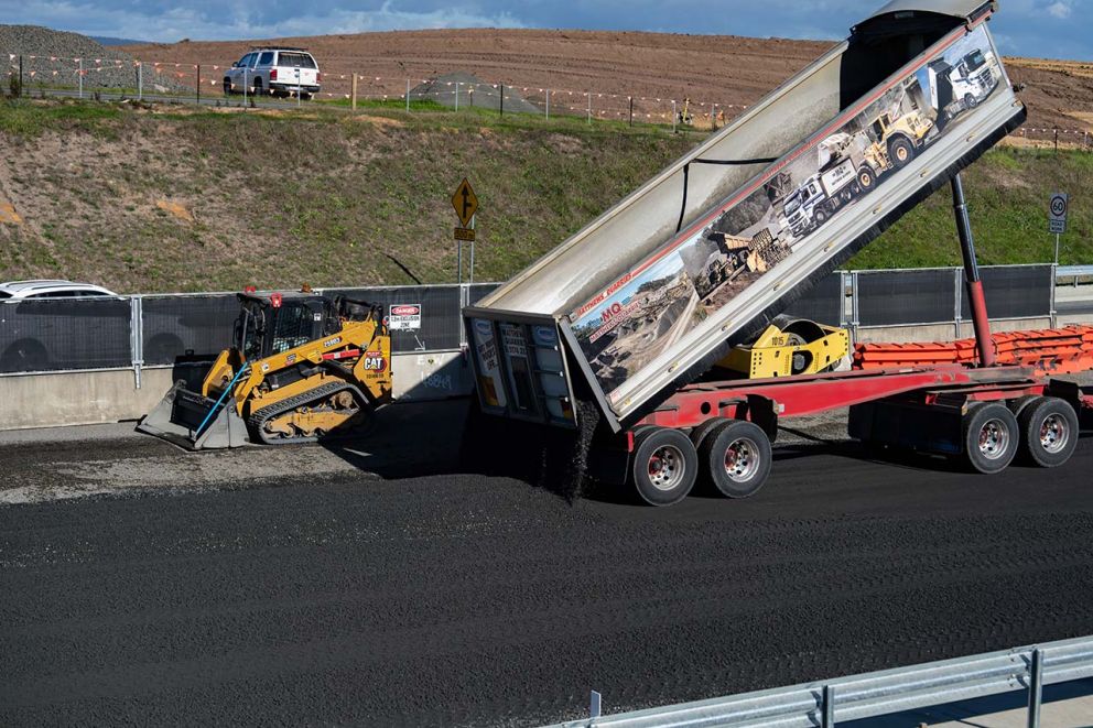 Truck off-loading asphalt material for track loader