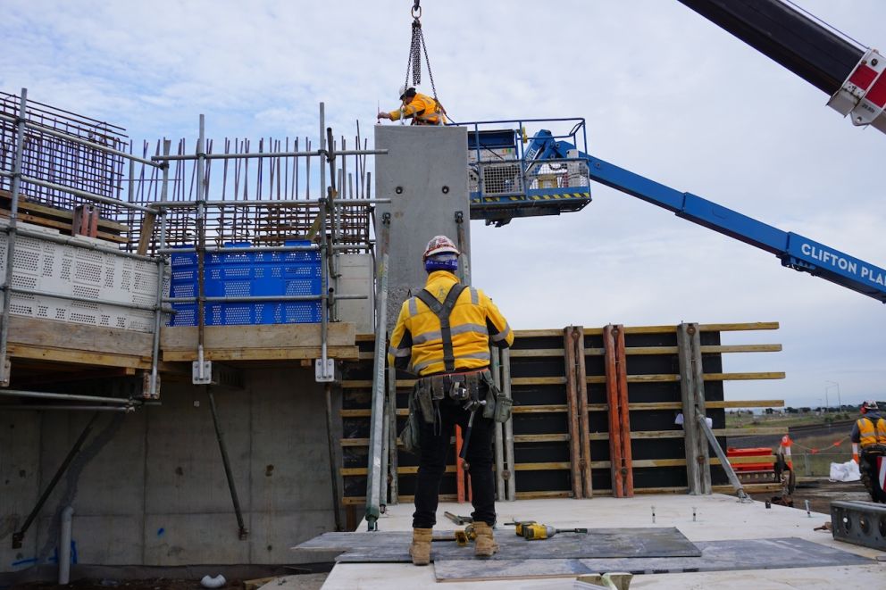 Crews carefully lift the first L-shaped panels into place in Truganina
