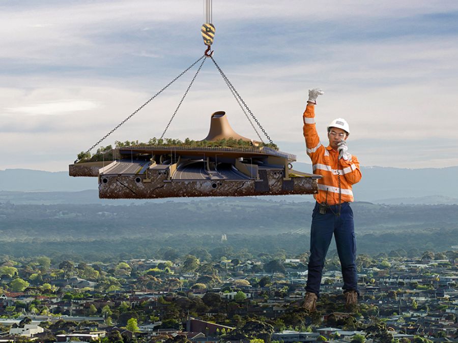 A giant construction worker moves a piece of road into place.