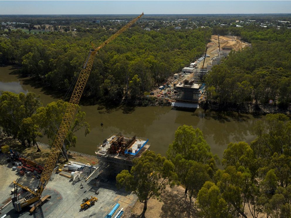 Mid-construction image of the Murray river bridge across the river with a crane present