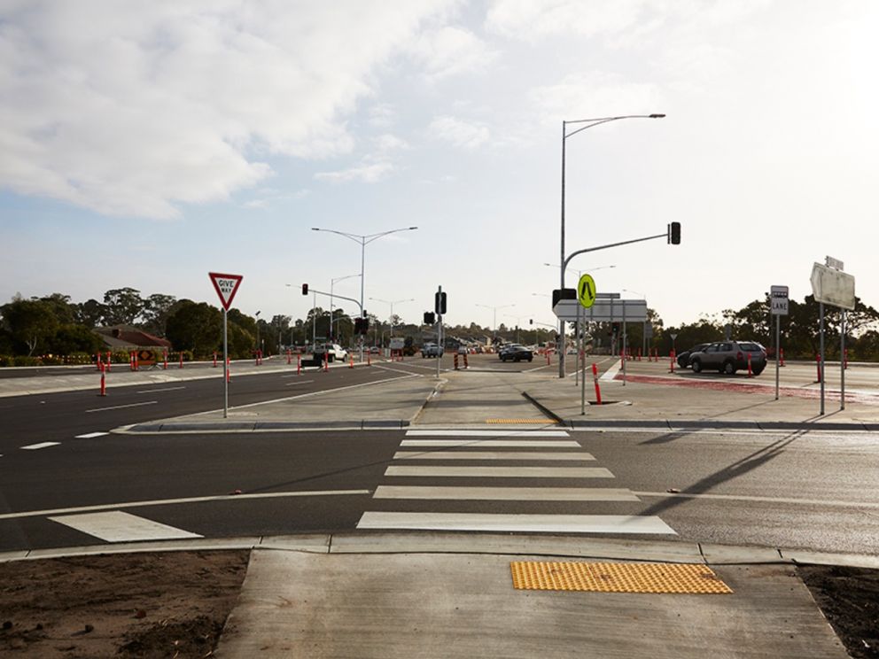 Image of the Hallam Rd intersection from the angle of one of the pedestrian crossings. Traffic can be seen in the distance