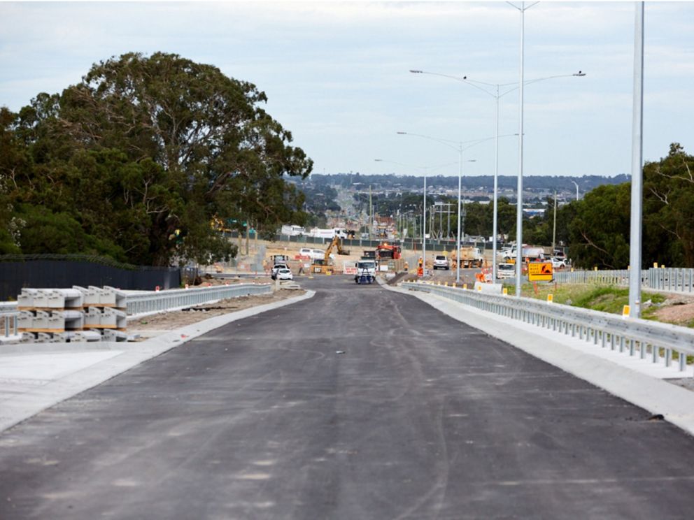 Image of Hallam Road with roadworks. This image highlights the newly laid road with trucks continuing work in the background