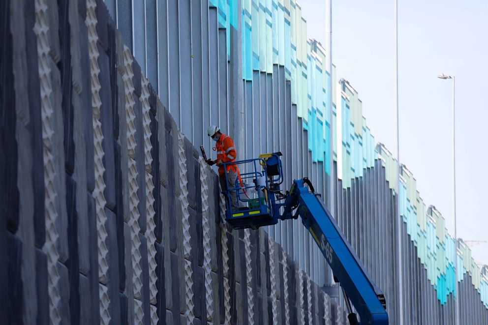 Crew in crane working on a noise wall