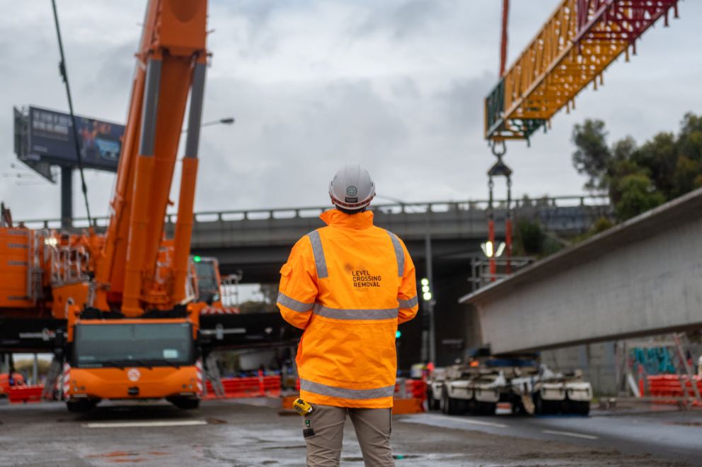 A construction worker watches as a 61-tonne bridge beam is raised.