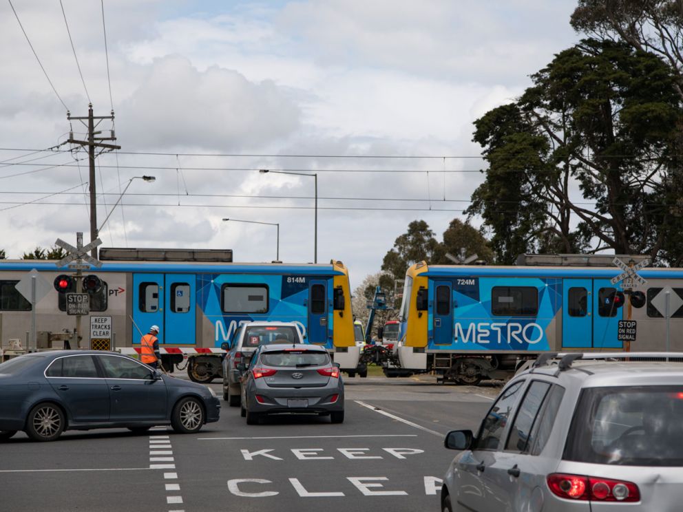 Train passing through McGregor Road level crossing with traffic waiting at boom gate.