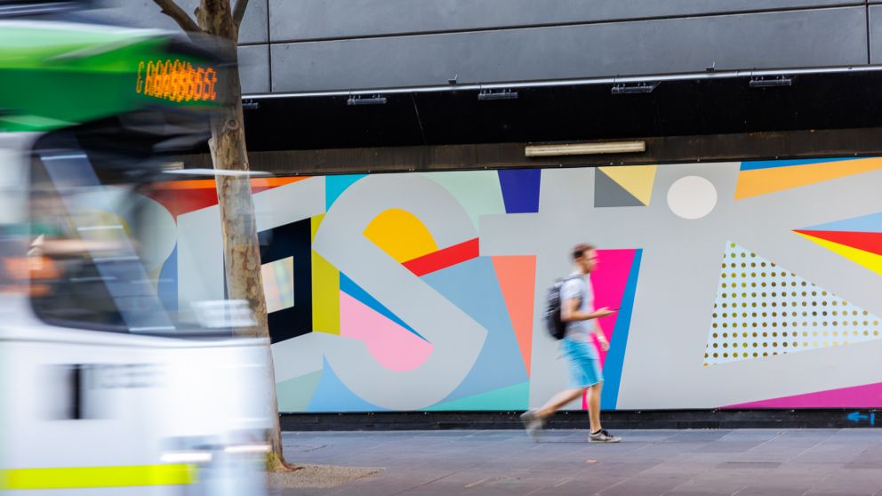  Photo of artwork, coloured shapes are seen on outside of typography.