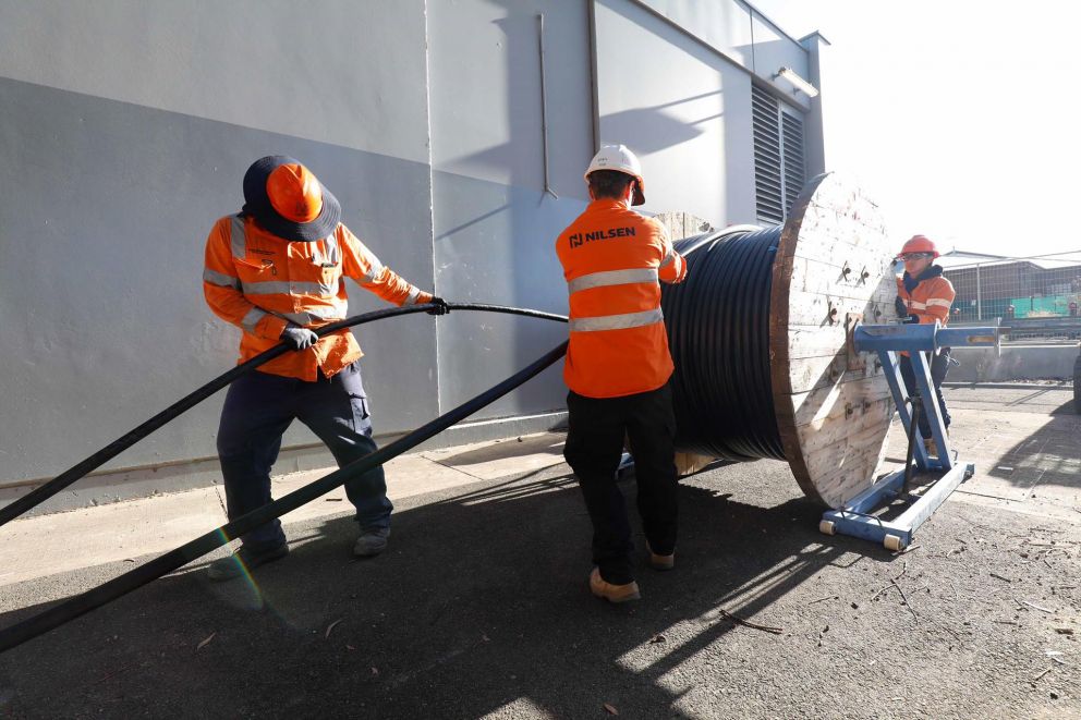 three workers pulling cables from wind 