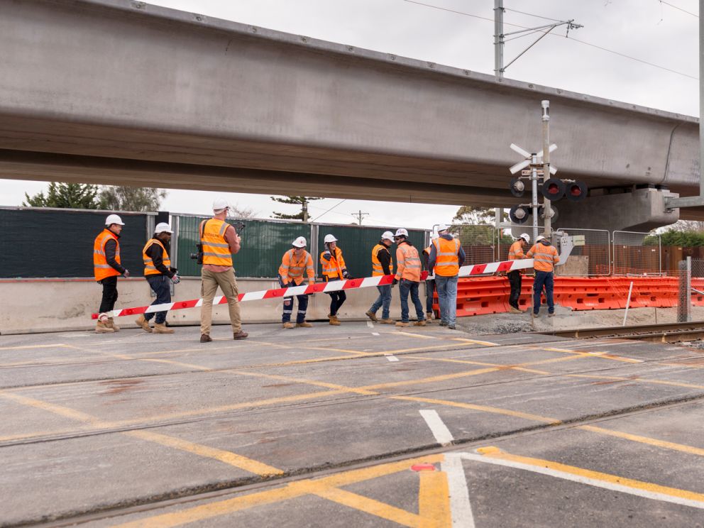 Group of people removing the boom gate with elevated rail behind.