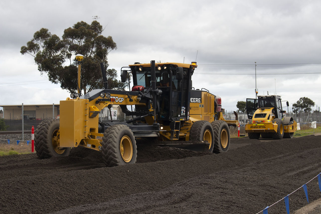 Spreading and compacting fill (dirt) to prepare the area for bridge foundation works