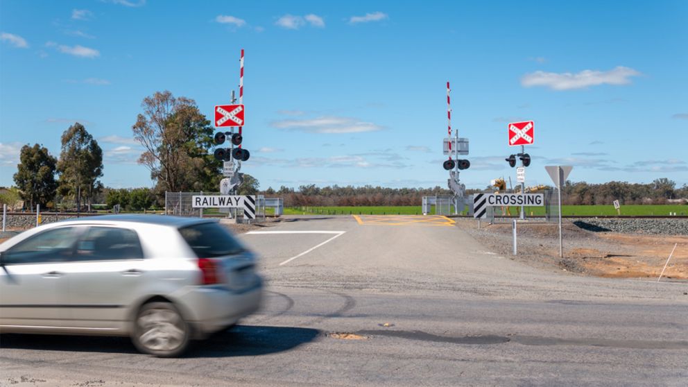 Car driving past level crossing