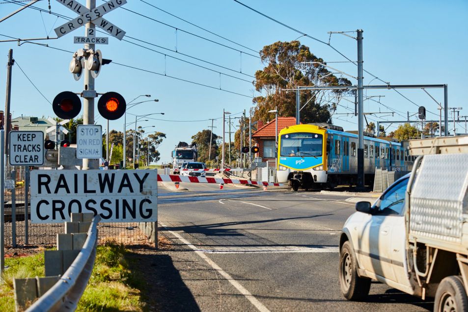 Traffic waiting at the Old Calder Highway level crossing as a train is passing through
