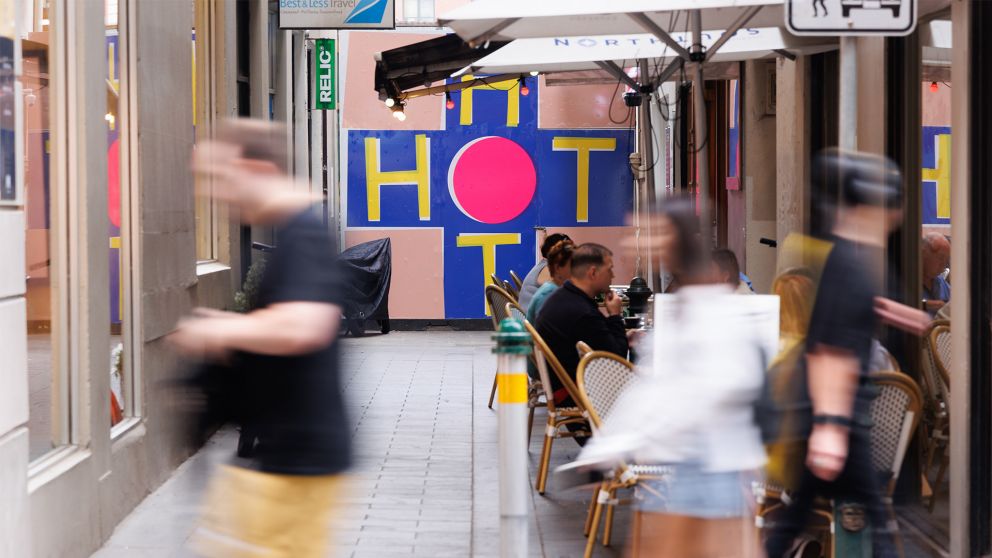 A colourful artwork with the word HOT on it is at the end of an alleyway